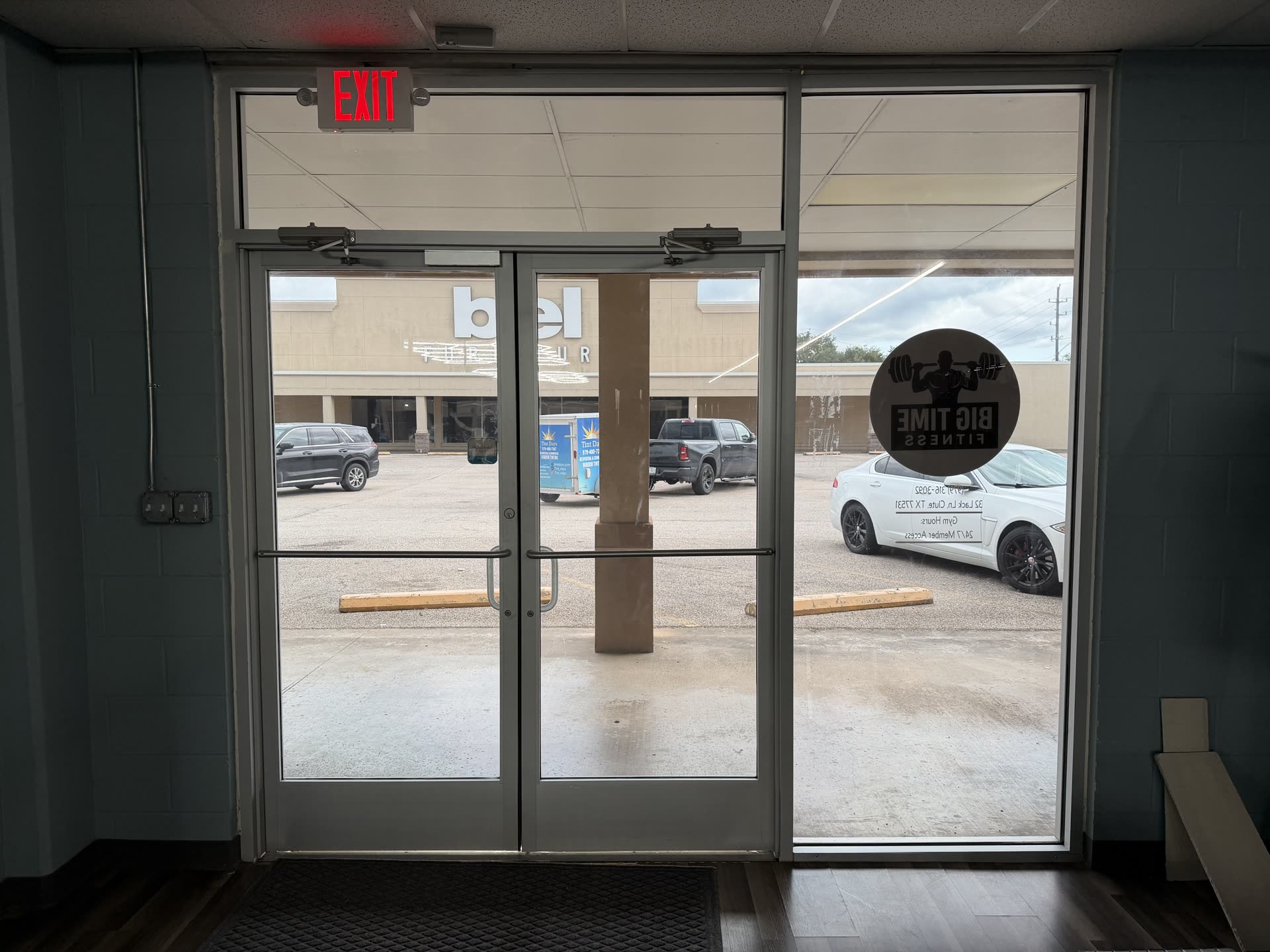 Looking out through the tinted front doors of Big Time Fitness in Clute