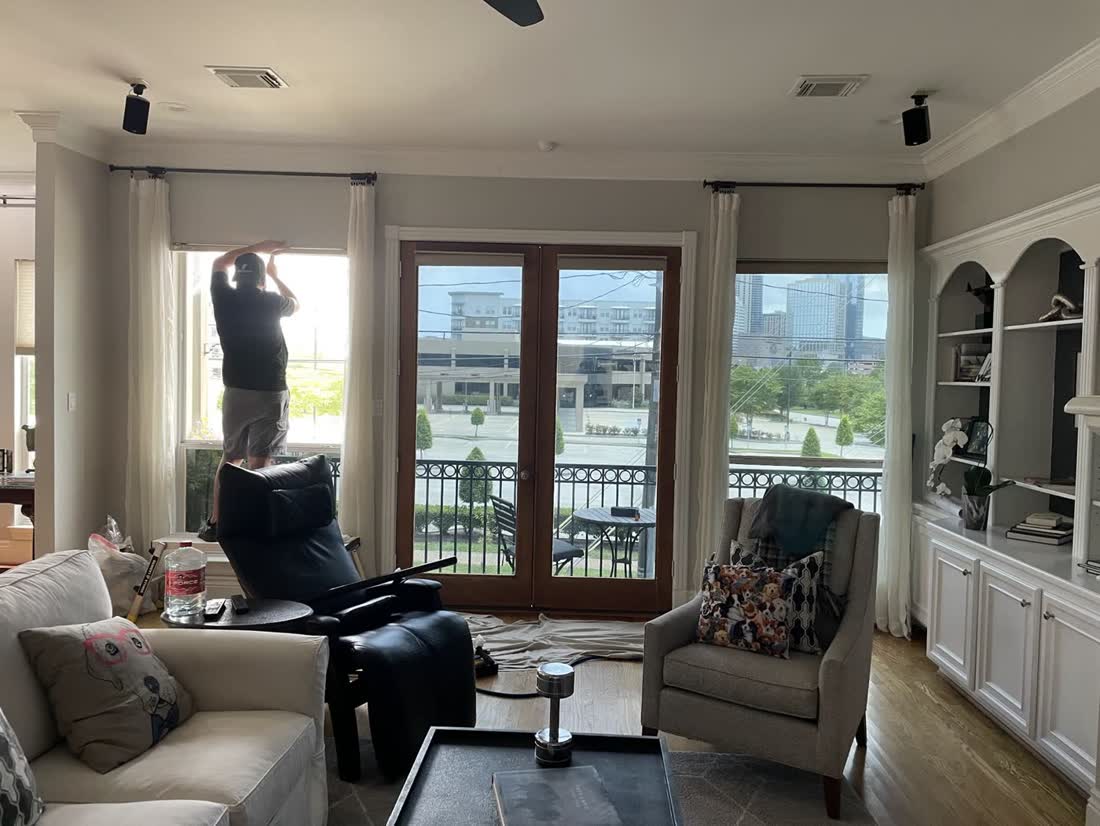 A Tint Days installer fitting film to the tall living room windows of a Houston home