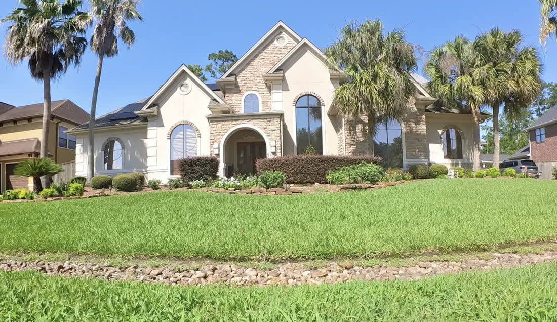 A Houston home with tinted windows, palms and a green lawn out front